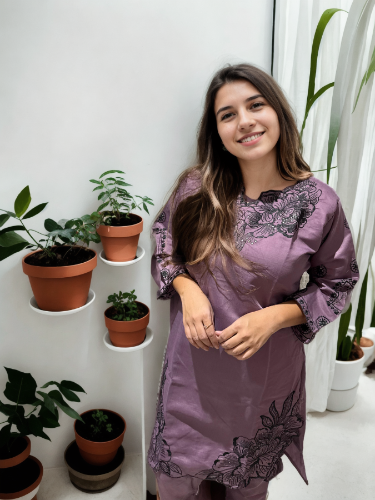 Woman in a purple dress standing in a room with plants